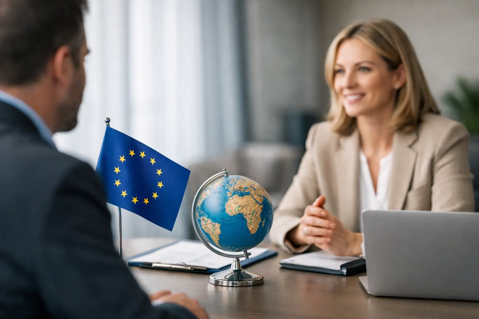 Adviser meeting a client with an EU flag and glass globe on the desk beside a laptop